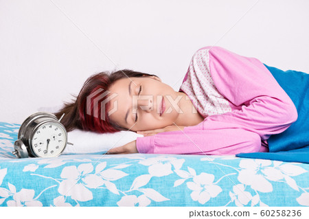 Girl in her bed sleeping next to the alarm clock Girl in her bed sleeping next to the alarm clock 60258236