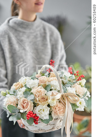 Flower arrangement in Wicker basket. Beautiful bouquet of mixed flowers in woman hand. Floral shop concept . Handsome fresh bouquet. Flowers delivery Flower arrangement in Wicker basket. Beautiful bouquet of mixed flowers in woman hand. Floral shop concept . Handsome fresh bouquet. Flowers delivery 60258489