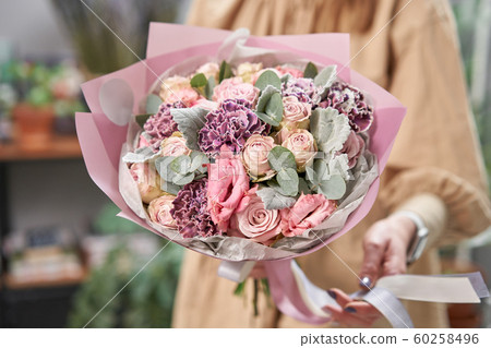 Modern floral shop. Finished work of the florist. Cute bouquet of mixed flowers in womans hands. Delivery fresh cut flower. Modern floral shop. Finished work of the florist. Cute bouquet of mixed flowers in womans hands. Delivery fresh cut flower. 60258496