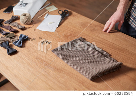 Tailor Selects wool from the stack. Young man working as a tailor and using a sewing machine in workshop. 60258594
