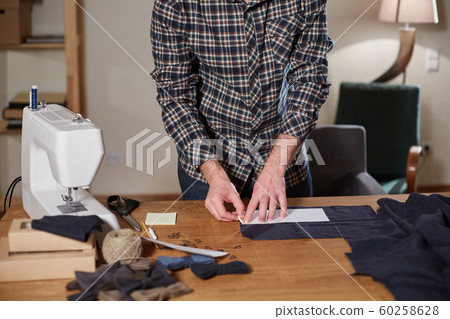 Tailor cutting wool fabric. the line pattern. Craftsman Makes rectangular blanks for Bow ties of woolen fabric. Work with sewing machine in a textile studio. Tailor cutting wool fabric. the line pattern. Craftsman Makes rectangular blanks for Bow ties of woolen fabric. Work with sewing machine in a textile studio. 60258628