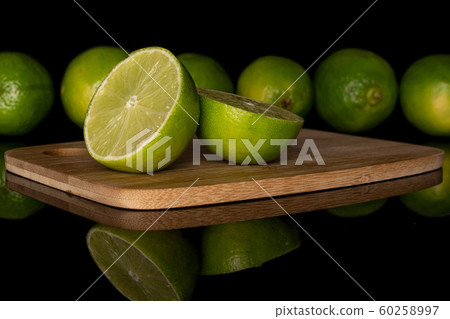Green sour lime isolated on black glass Green sour lime isolated on black glass 60258997