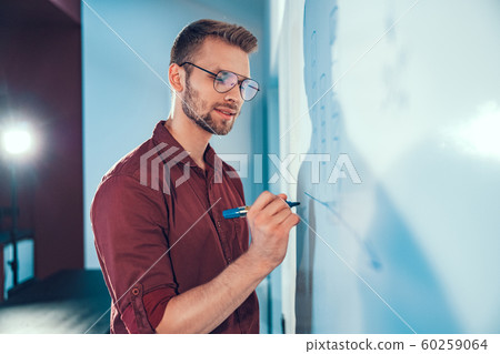 Young man is standing near white wall 60259064