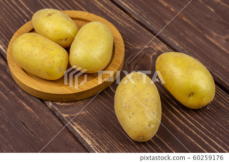 Yellow pale potato on brown wood 60259176