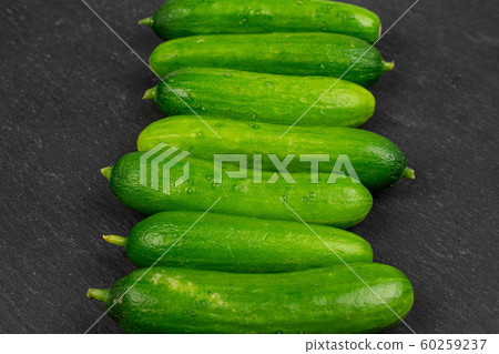 Fresh green baby cucumber on grey stone Fresh green baby cucumber on grey stone 60259237