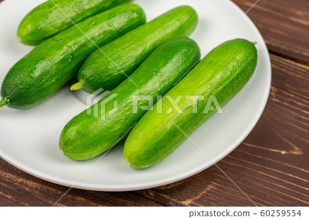 Fresh green baby cucumber on brown wood Fresh green baby cucumber on brown wood 60259554