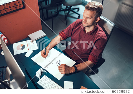 Young male employee looking seriously at the monitor screen Young male employee looking seriously at the monitor screen 60259922