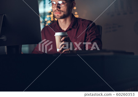 Young man is holding hot drink in office 60260353