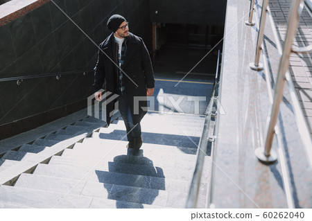 Caucasian guy keeeping his bag and walking in city 60262040