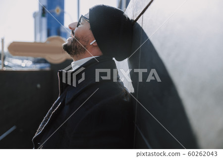 Caucasian bearded man leaning on the wall outside 60262043