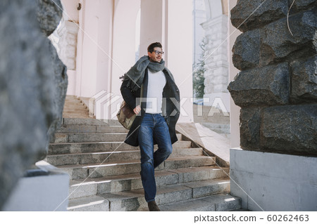 Caucasian man in coat is walking downstairs 60262463