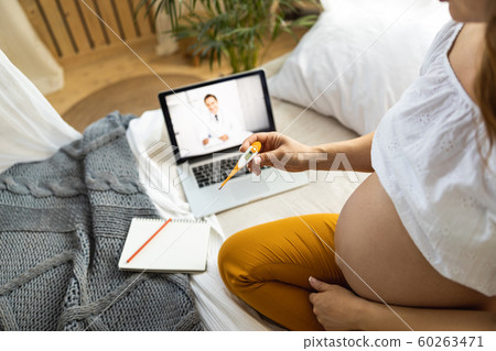 Pregnant woman is holding thermometer in hand 60263471