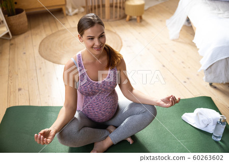 Smiling pregnant lady doing yoga at home Smiling pregnant lady doing yoga at home 60263602