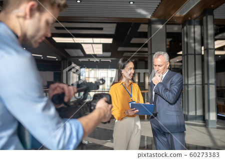 Asian female reporter in beige pants making motes 60273383
