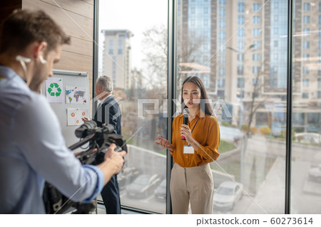 Dark-haired female reporter talking to the videocamera Dark-haired female reporter talking to the videocamera 60273614