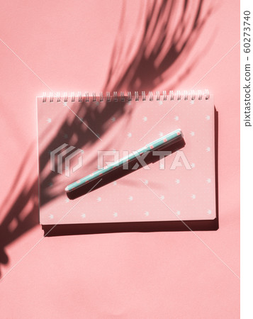 Pink notebook with pen and tropical plant shadow Pink notebook with pen and tropical plant shadow 60273740