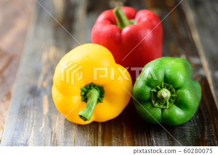 Yellow, green and red bell peppers on wooden background Yellow, green and red bell peppers on wooden background 60280075