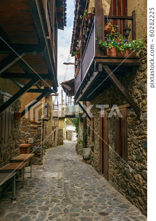 Ancient village Kakopetria in Cyprus - travel architecture background. Stunning view of the street in old town. Pots with flowers standing on paved pavement along stone wall Ancient village Kakopetria in Cyprus - travel architecture background. Stunning view of the street in old town. Pots with flowers standing on paved pavement along stone wall 60282225