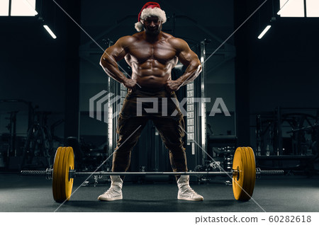 Bodybuilder in Santa Claus costume in the gym Bodybuilder in Santa Claus costume in the gym 60282618
