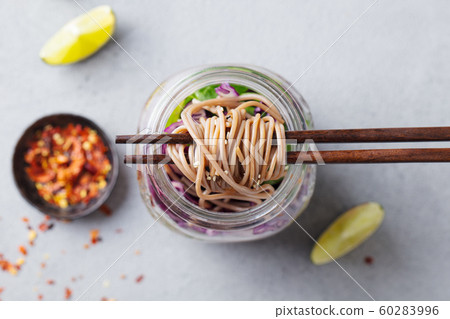 Noodles soba salad, soup with vegetables, tofu and chicken in jars. Grey background. Close up. Top view. Noodles soba salad, soup with vegetables, tofu and chicken in jars. Grey background. Close up. Top view. 60283996