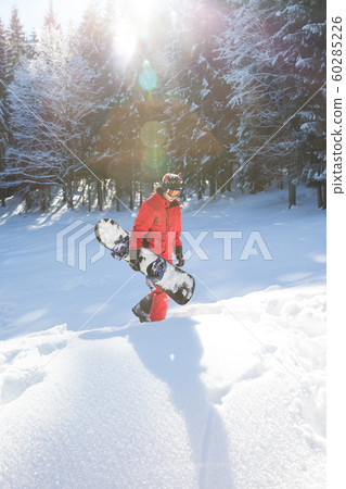 Freerider with snowboard in hands at snowy spruce Freerider with snowboard in hands at snowy spruce 60285226