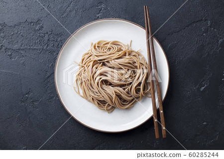 Soba noodles on a white plate. Japanese food. Black slate background. Top view. Soba noodles on a white plate. Japanese food. Black slate background. Top view. 60285244