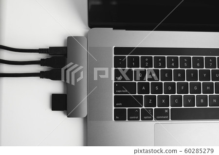 Laptop with USB Type-C adapter with pluged USB cables and SD card. The USB adapter under the Type-C connector for laptop. Multiport station for laptop with multiple different ports. Hub Converter. 60285279
