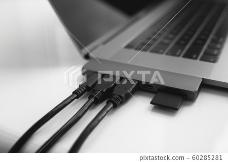 Laptop with USB Type-C adapter with pluged USB cables and SD card. The USB adapter under the Type-C connector for laptop. Multiport station for laptop with multiple different ports. Hub Converter. 60285281