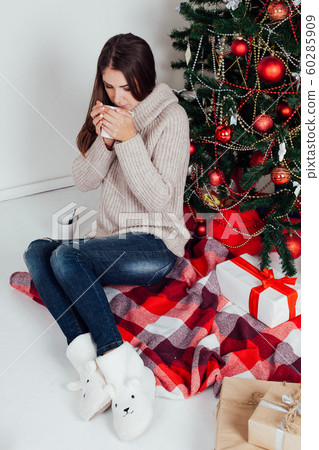 girl drinking coffee under the Christmas tree new year tea 60285909