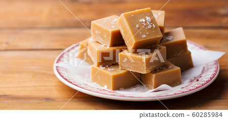 Caramel fudge candies on a plate. Wooden background. Close up. Caramel fudge candies on a plate. Wooden background. Close up. 60285984