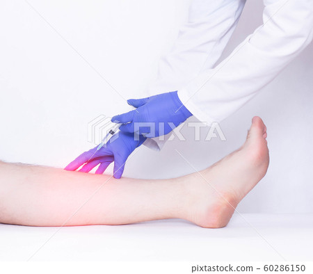 The doctor makes an injection into the calf muscle to the patient of an anti-inflammatory drug to relieve pain and inflammation, stretching the ligament on the leg The doctor makes an injection into the calf muscle to the patient of an anti-inflammatory drug to relieve pain and inflammation, stretching the ligament on the leg 60286150