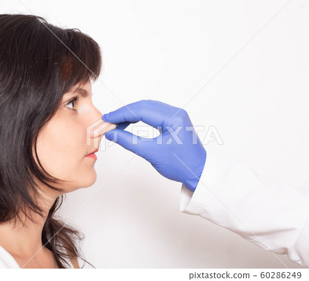 Doctor plastic surgeon examines the patient's nose before surgery. Rhinoplasty concept of the nose, copy space, secondary rhinoplasty Doctor plastic surgeon examines the patient's nose before surgery. Rhinoplasty concept of the nose, copy space, secondary rhinoplasty 60286249