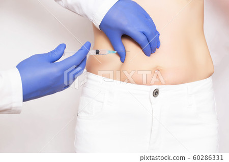 Doctor cosmetologist makes Botox injections and rejuvenation in the stomach of a girl. Smoothing wrinkles and wrinkles on the abdomen with the help of hyaluronic acid rejuvenation injections 60286331