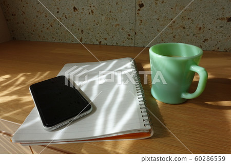 Cup, notebook, phone under the sun shine through the coffee cup, smartphone and notebook curtain Cup, notebook, phone under the sun shine through the coffee cup, smartphone and notebook curtain 60286559