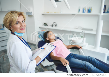 Smiling dentist is making diagnosis for young lady 60287365