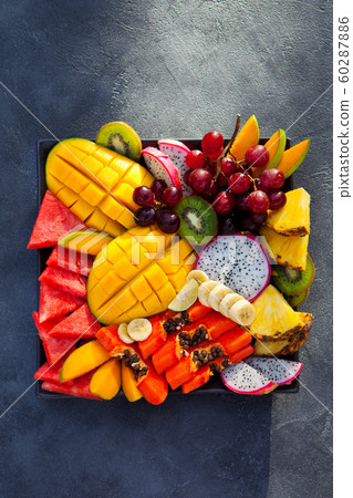Tropical fruits assortment on a plate. Slate background. Copy space. Top view. Tropical fruits assortment on a plate. Slate background. Copy space. Top view. 60287886