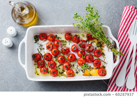 Roasted cherry tomatoes with herbs in baking dish. Grey background. Top view. 60287937