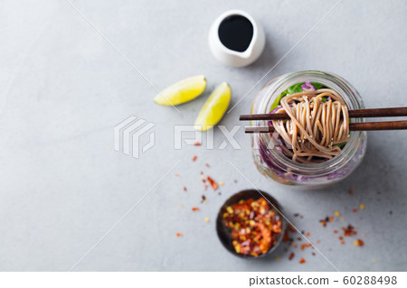 Noodles soba salad, soup with vegetables, tofu and chicken in jars. Grey background. Top view. Copy space. Noodles soba salad, soup with vegetables, tofu and chicken in jars. Grey background. Top view. Copy space. 60288498