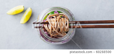 Noodles soba salad, soup with vegetables, tofu and chicken in jars. Grey background. Close up. Top view. 60288500