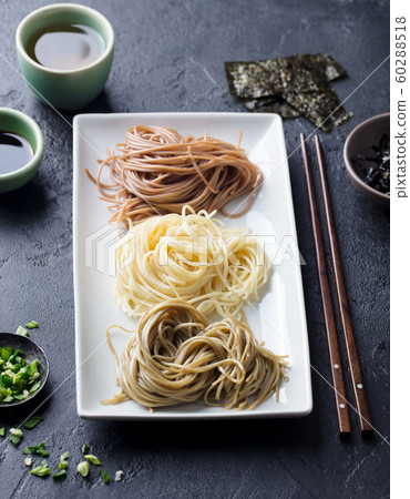 Assortment of Japanese soba noodles with sauce and garnishes. Black slate background. 60288518