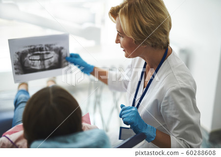 Pleasant nice female dentist holding a dental scan Pleasant nice female dentist holding a dental scan 60288608