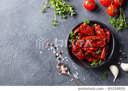 Sun dried tomatoes with fresh herbs and spices. Slate background. Top view. Copy space. 60288689