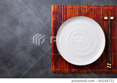 Asian table place setting with white plate and chopsticks. Top view. Copy space. Grey background. 60288712