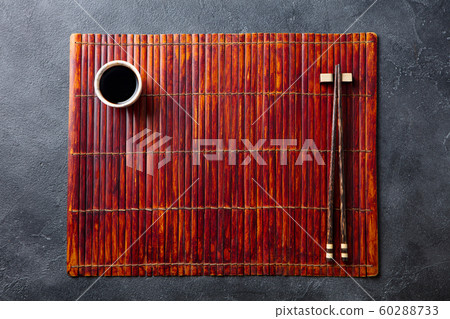 Asian table place setting with bamboo placemat, sauce bowl and chopsticks. Top view. Copy space. 60288733