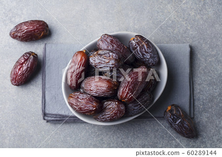 Fresh Medjool Dates in a bowl. Ramadan kareem. Grey stone background. Top view. Fresh Medjool Dates in a bowl. Ramadan kareem. Grey stone background. Top view. 60289144
