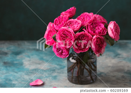 Peony roses bunch in glass vase. Blue stone background. Copy space. 60289169