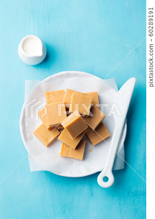 Fresh caramel fudge candies on a plate. Blue background. Top view. 60289191