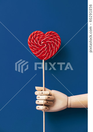 Wooden hand holding a large blue and white striped lollipop Wooden hand holding a large blue and white striped lollipop 60291856