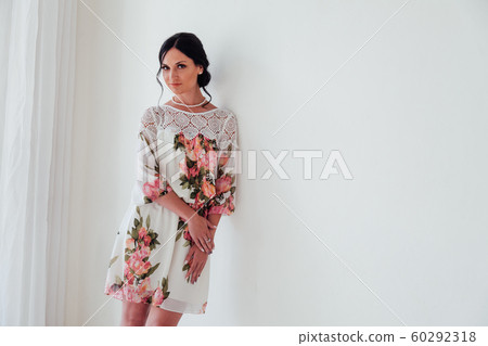 Portrait of a beautiful fashionable brunette woman in a dress with flowers 60292318