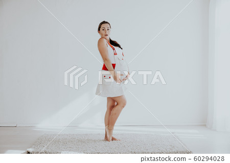 pregnant woman posing in a white room pregnant woman posing in a white room 60294028